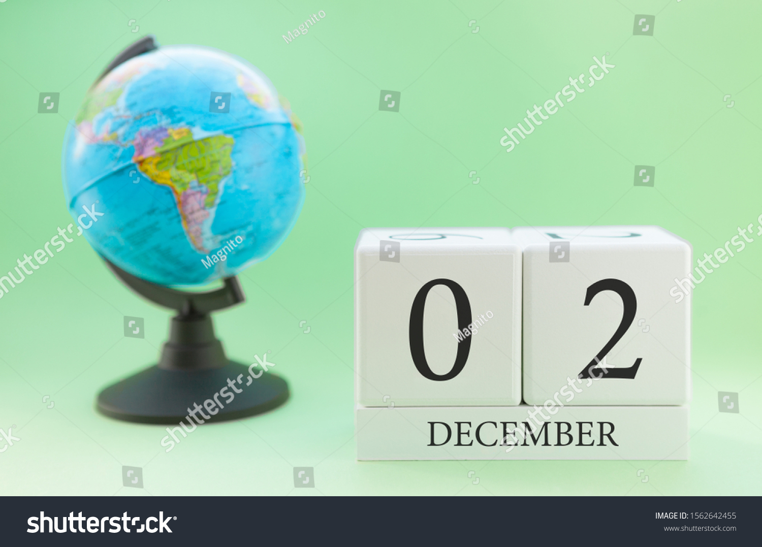 December 2. December month. White cube with numbers and globe on a blurred green background. The concept of New Year and Christmas holidays. #1562642455