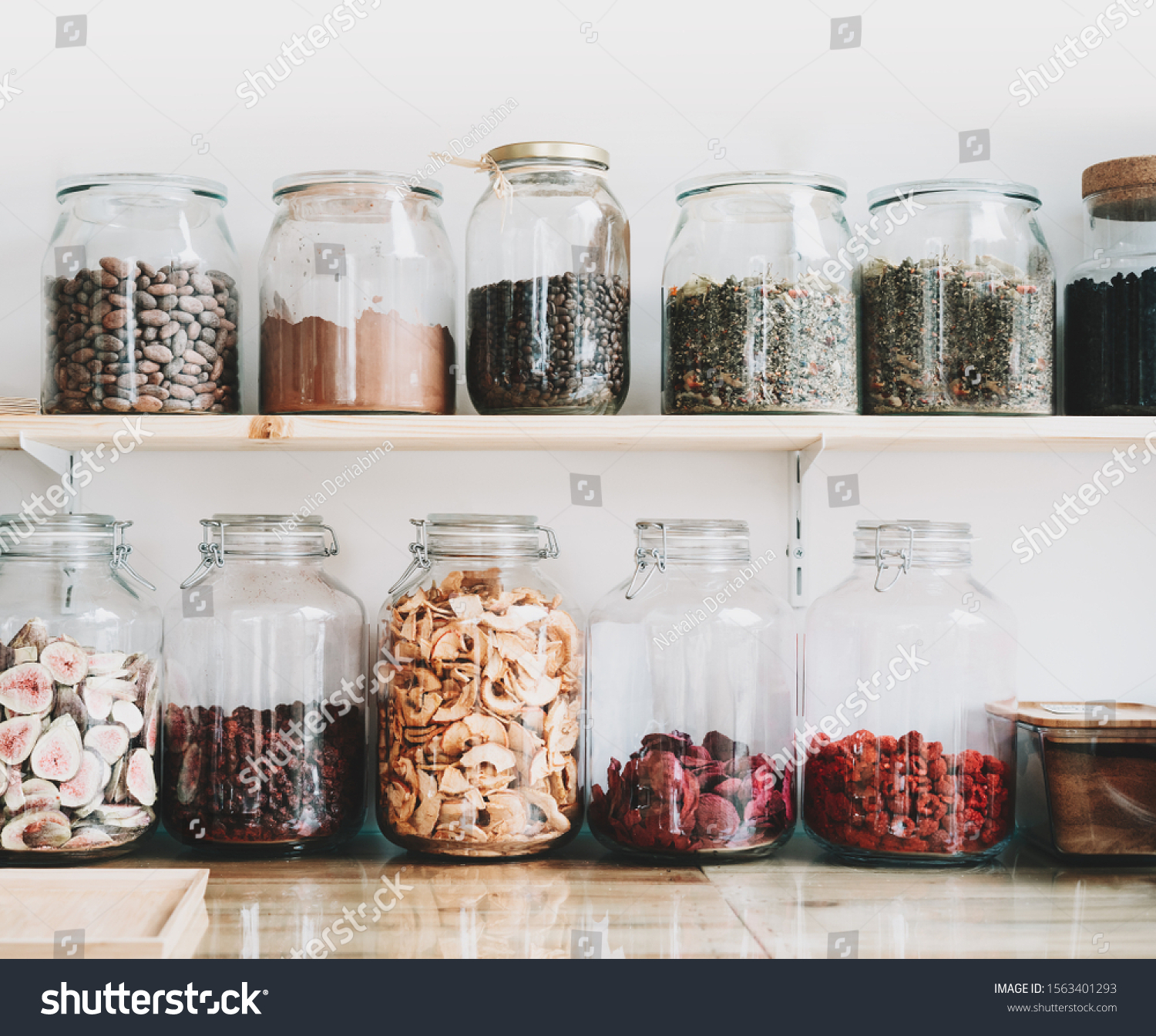 Organic bulk products in zero waste shop. Foods storage in kitchen at low waste lifestyle. Dried berries and fruits in glass jars on shelves. Eco friendly shopping in plastic free grocery store. #1563401293