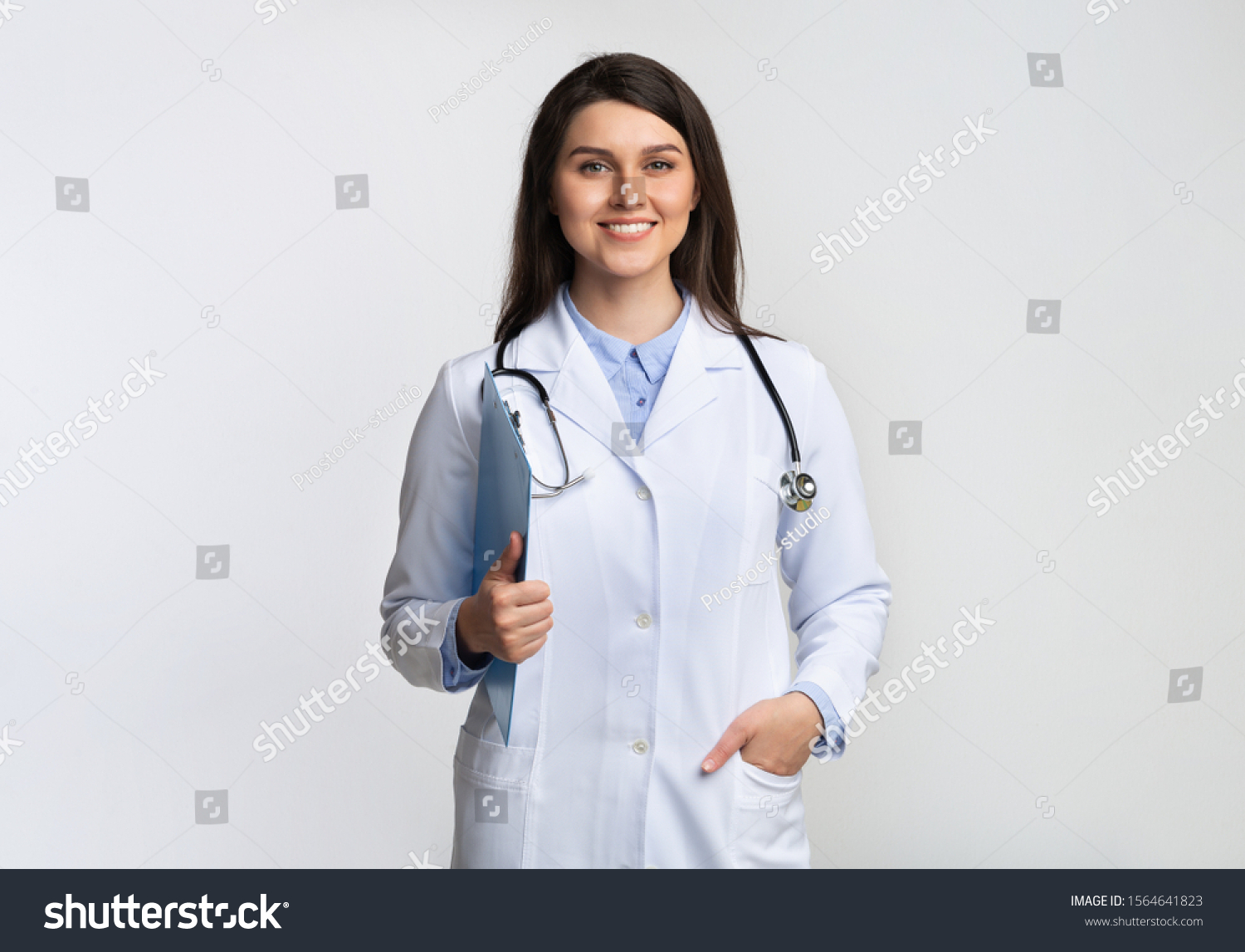 Doctor. Positive Therapist Lady Smiling At Camera Holding Folder Standing Over Gray Background. Studio Shot #1564641823