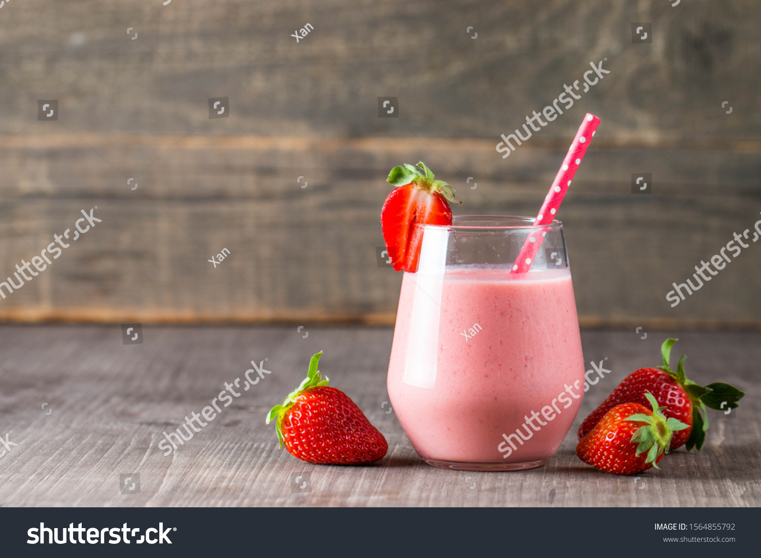 Glass of fresh strawberry milkshake, smoothie and fresh strawberries on pink, white and wooden background. Healthy food and drink concept. #1564855792