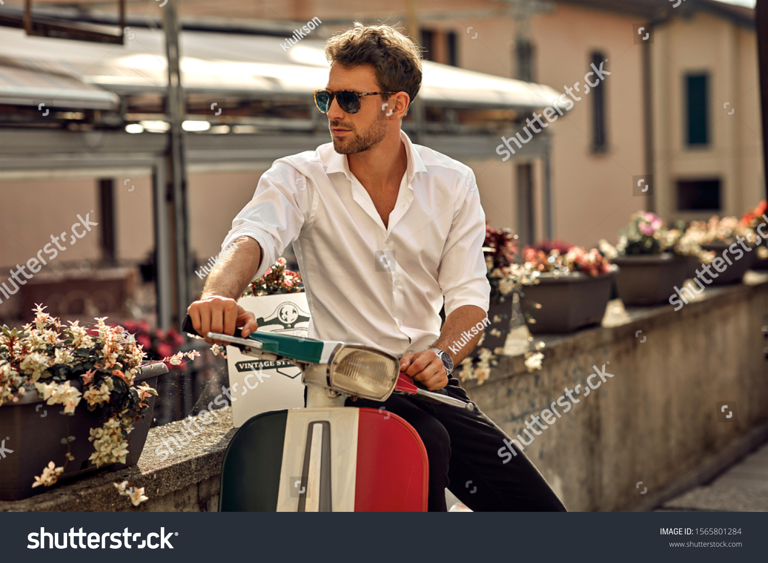 Stylish italian man wearing white shirt and sitting on classic scooter #1565801284