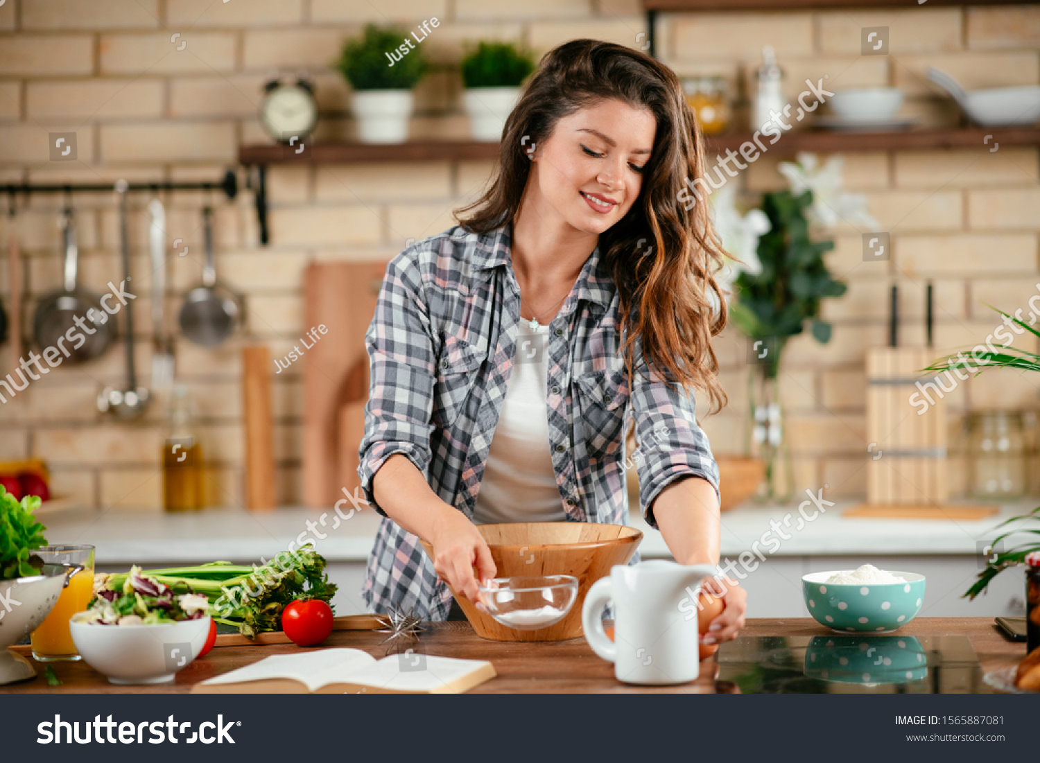 Beautiful young woman cooking in kitchen. Woman preparing pancakes. #1565887081