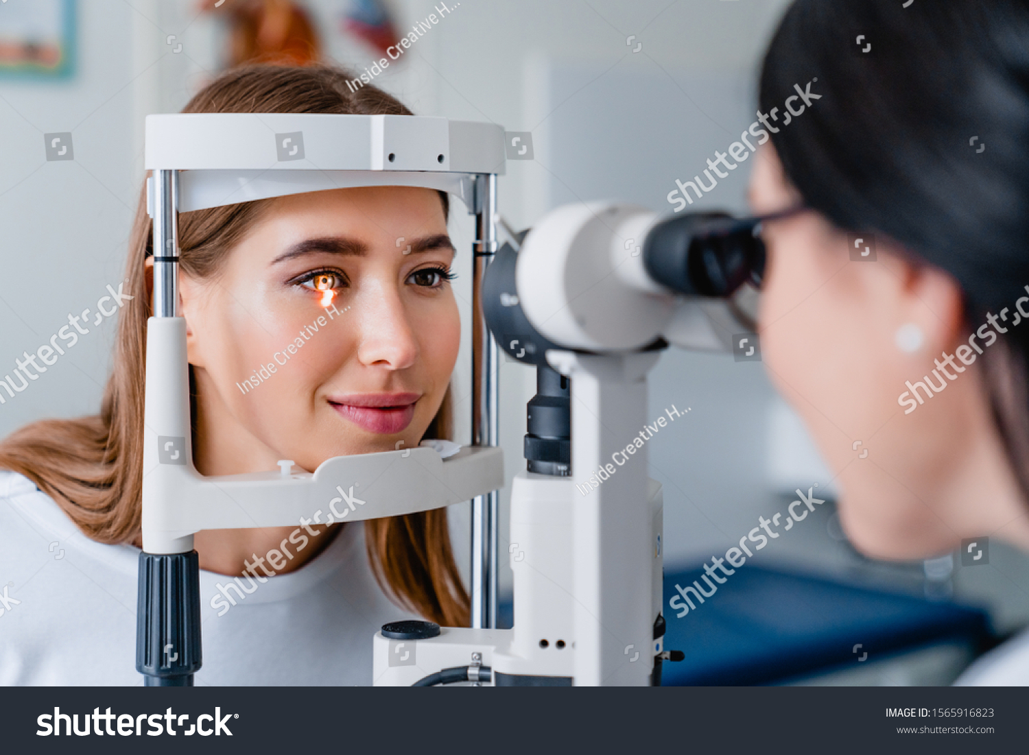 Eye doctor with female patient during an examination in modern clinic #1565916823