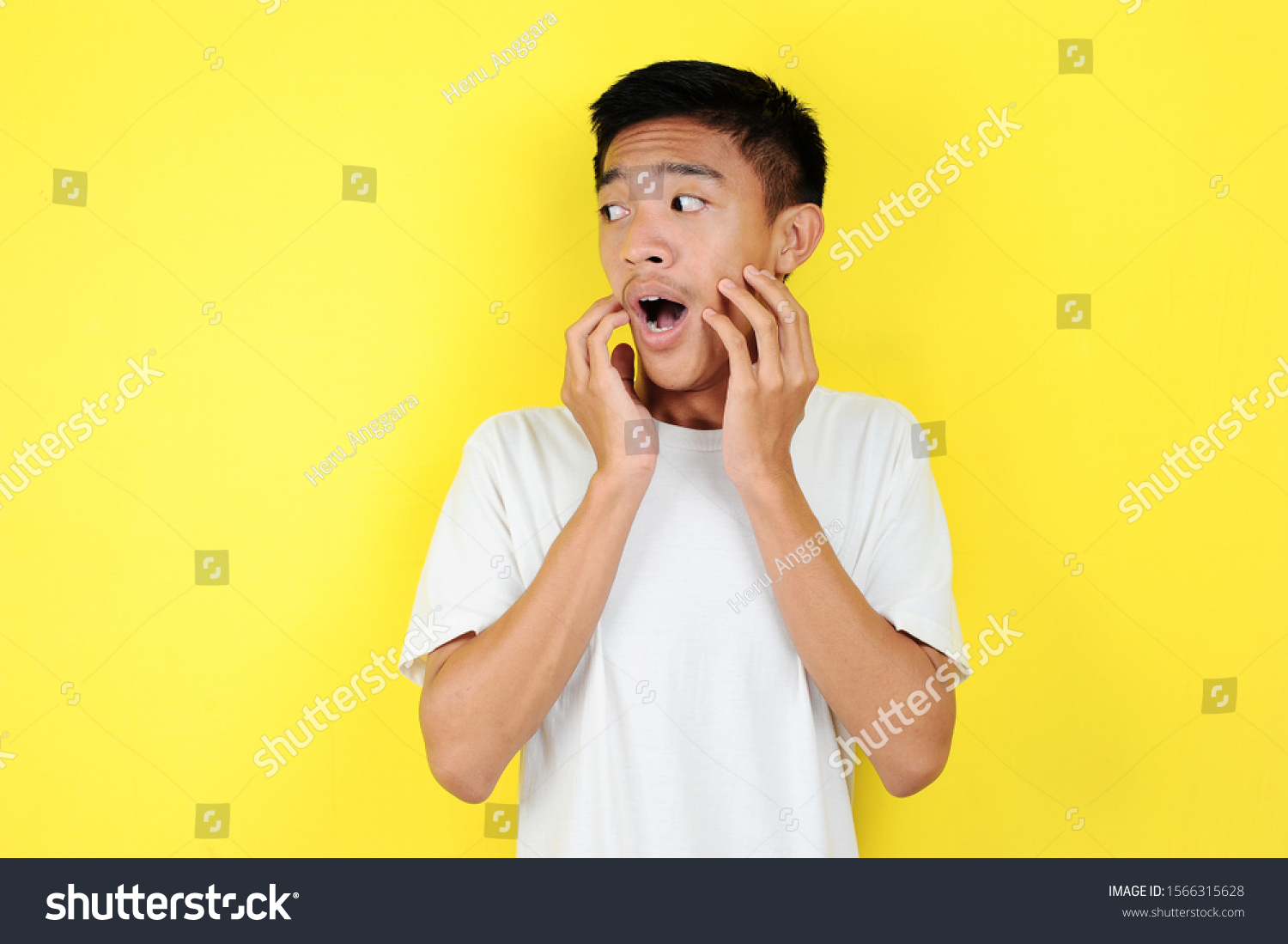 Shocked face of Asian man in white shirt on yellow background. #1566315628