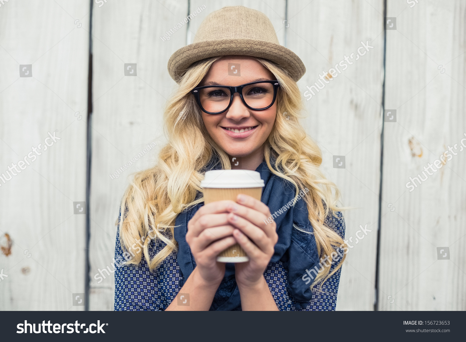 Cheerful fashionable blonde holding coffee outdoors on wooden background #156723653