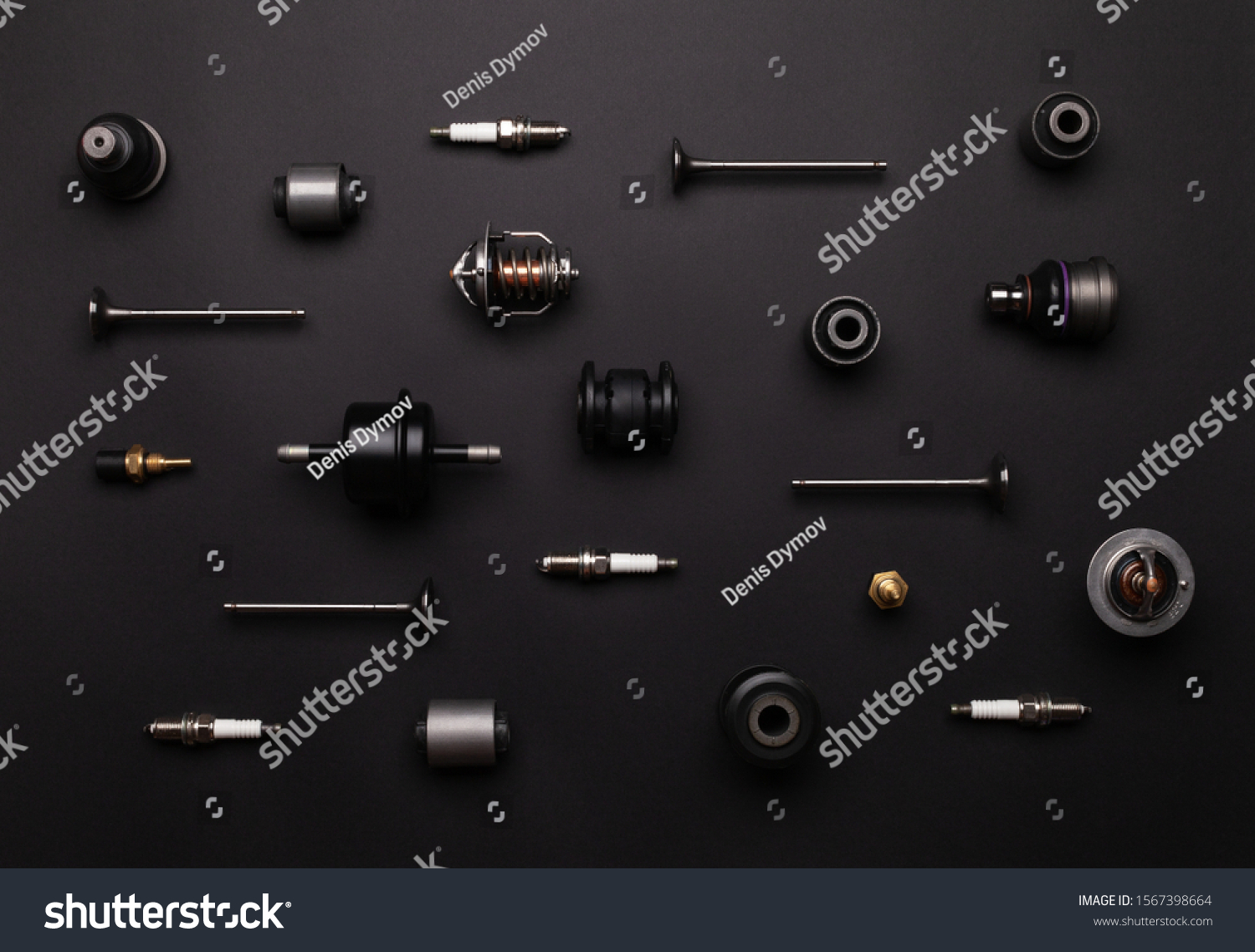 Studio photography - a lot of automotive parts: valves, spark plugs, silent blocks, thermostats, filter, sensors, ball bearings, lie in straight rows on a flat surface isolated on a black background. #1567398664