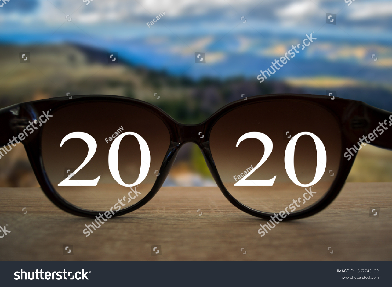 2020 white text with black eye glasses on wooden table over blur autumn landscapes. Business vision happy new year. #1567743139