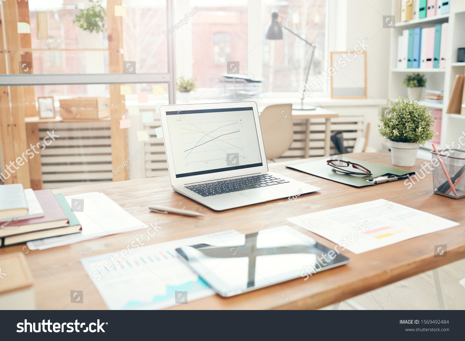 Background image of modern office interior with laptop on wooden table, workplace design concept, copy space #1569492484