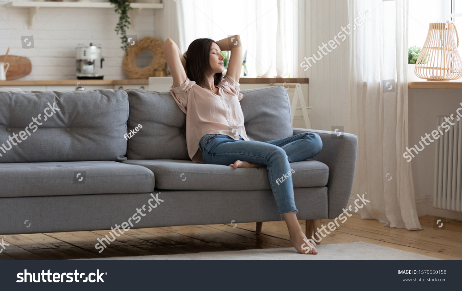 Serene lady housewife lounge sit on sofa feel fatigue napping hold hands behind head, calm young woman rest on comfort couch with eyes closed breath fresh air in cozy clean modern living room at home #1570550158