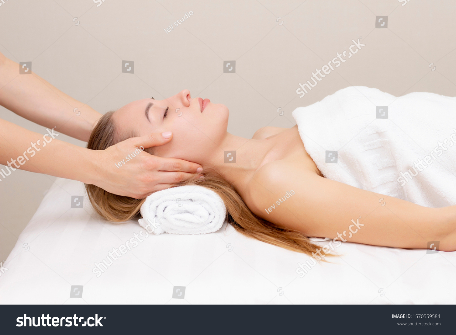 Young woman enjoying massage in spa salon. Face massage. Closeup of young woman getting spa massage treatment at beauty spa salon.Spa skin and body care. Facial beauty treatment.Cosmetology.  #1570559584