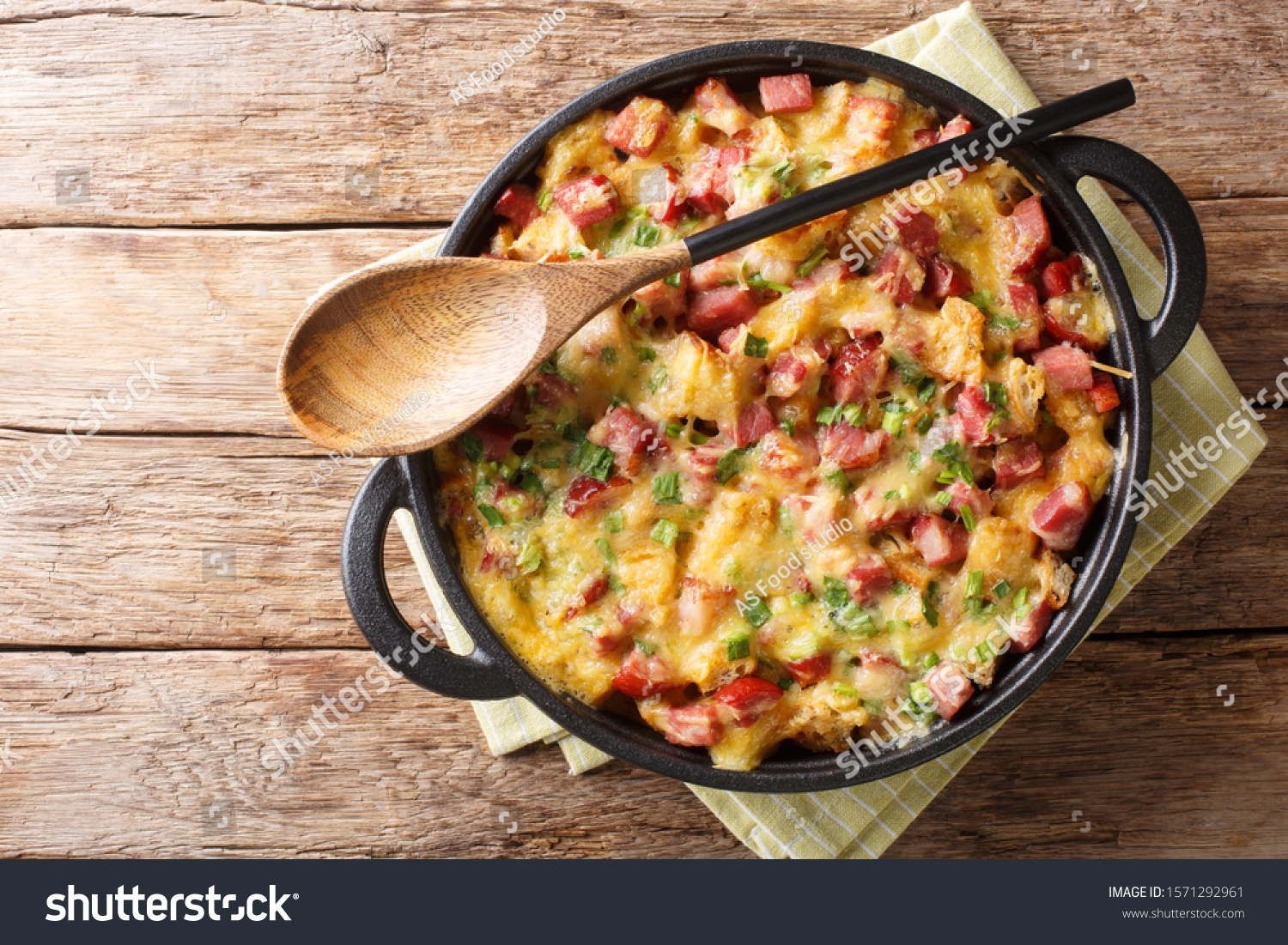 Tasty hot homemade strata with ham, onions, cheese and eggs close-up in a pan on the table. Horizontal top view from above
 #1571292961