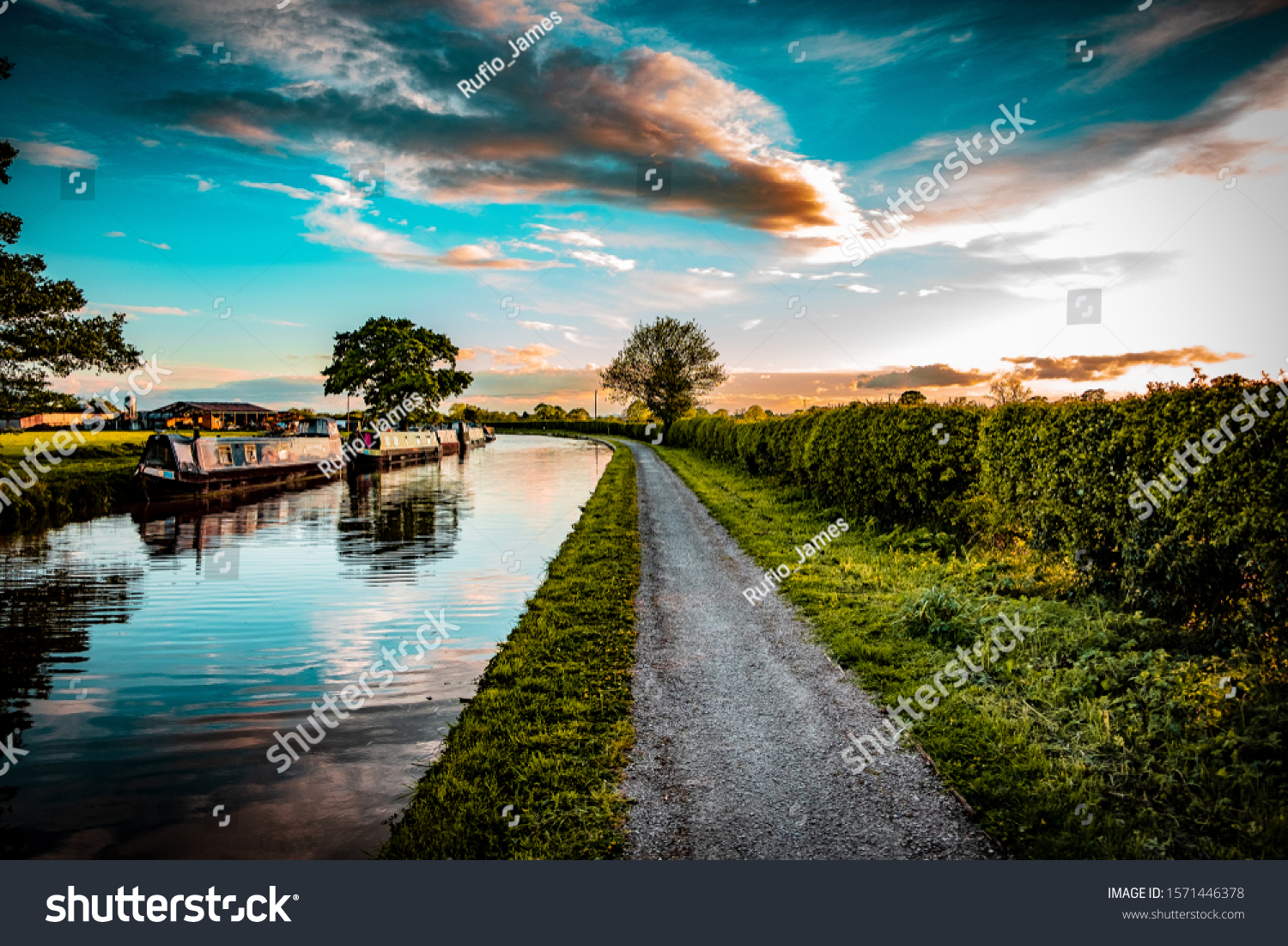 Cheshire Countryside Canal scene, with barges, trees and farm fields set in the Uk summertime at sunset. #1571446378