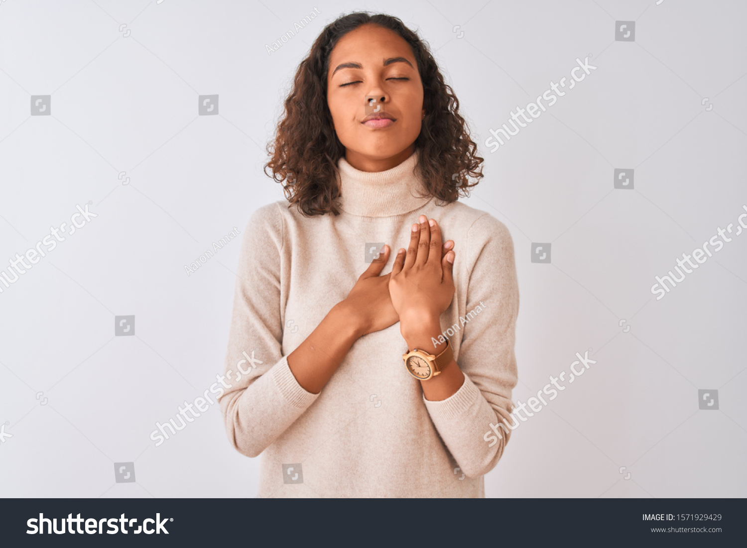 Young brazilian woman wearing turtleneck sweater standing over isolated white background smiling with hands on chest with closed eyes and grateful gesture on face. Health concept. #1571929429