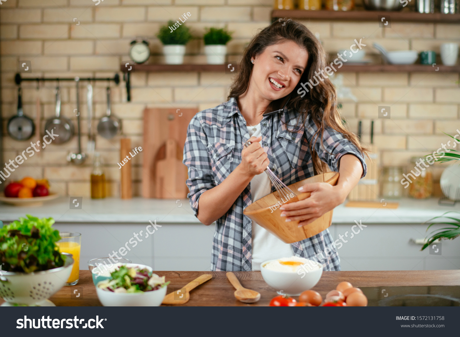 Portrait of beautiful young woman cooking in the kitchen. 
Young Woman Cooking. Healthy Food - Vegetable Salad. #1572131758