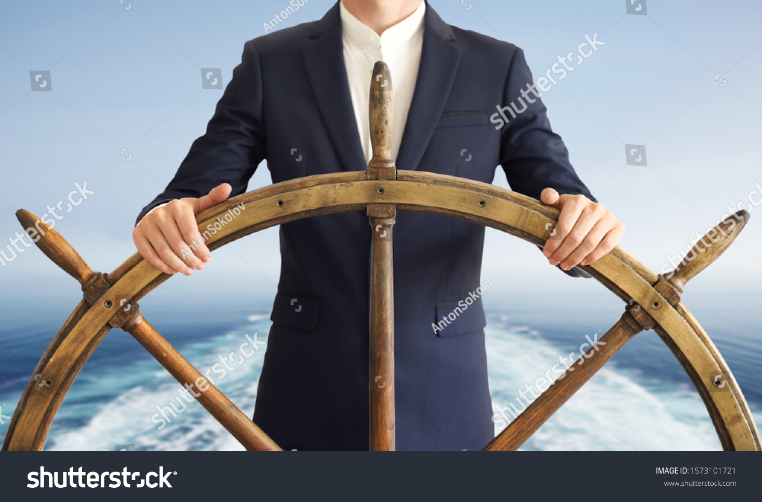 Businessman holding ship rudder with blue sea on background. Leader Concept. #1573101721