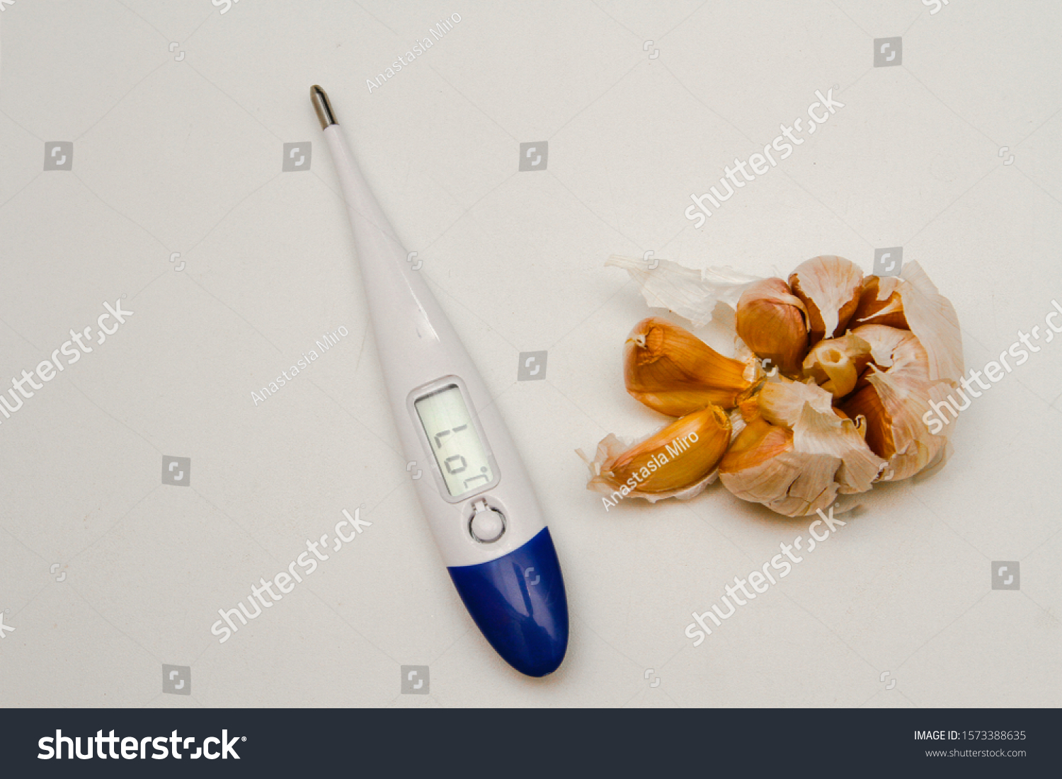 thermometer and garlic on a white background for the prevention of colds top view . Flu and cold season. Maintain health #1573388635