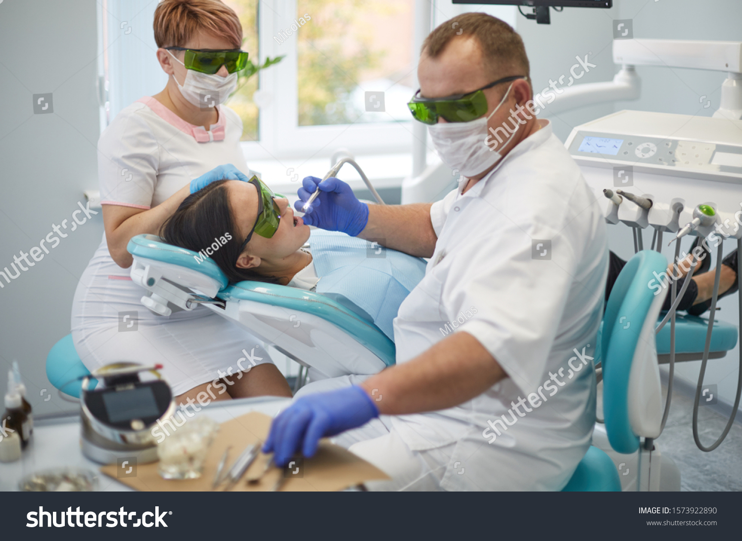 Doctor dentist treats teeth of a beautiful young girl patient. #1573922890