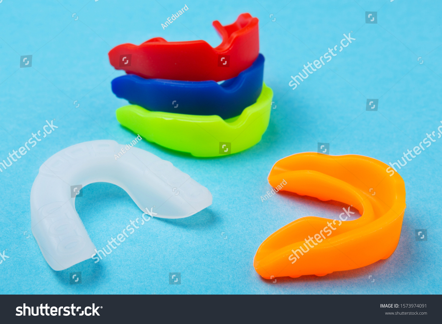 many colored boxing mouth guards lie on a blue background, sports concept #1573974091