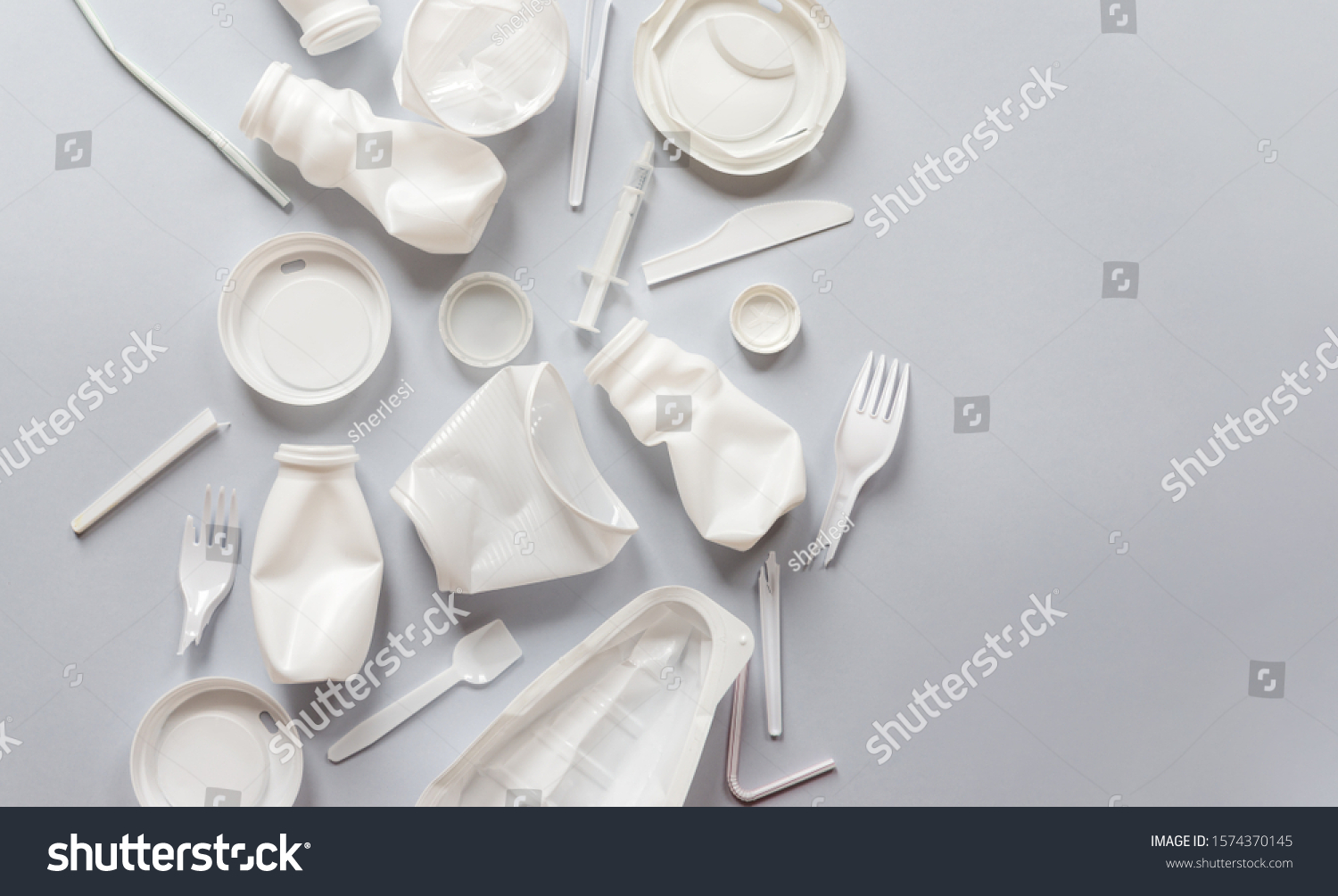 Used white plastic packaging for food on a gray background. The concept of protecting the environment from plastic waste contamination. Flat lay #1574370145