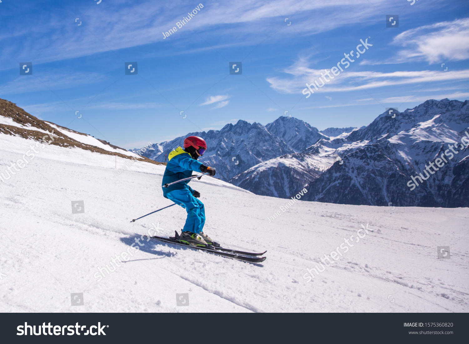 Little boy in blue and yellow ski costume skiing in downhill slope. Winter sport recreational activity #1575360820