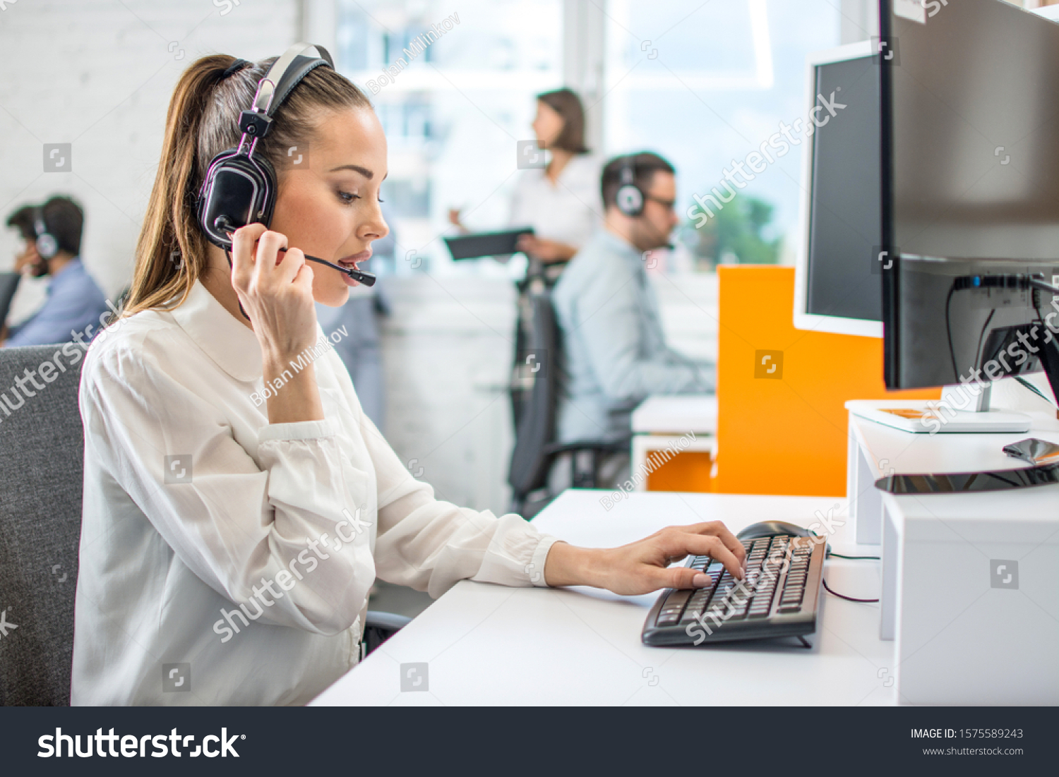 Beautiful female call center operator working on computer in office #1575589243