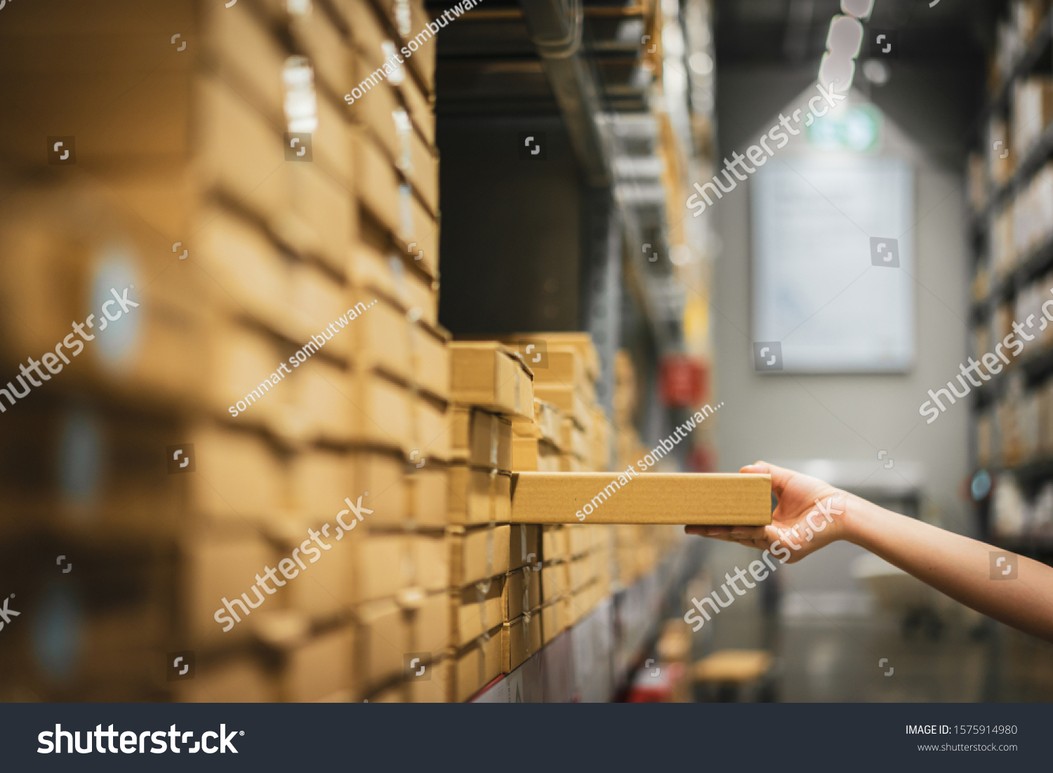 Cardboard box package with blur hand of Asian shopper woman picking product from shelf in warehouse. customer shopping lifestyle in department store or purchasing factory good concepts. #1575914980