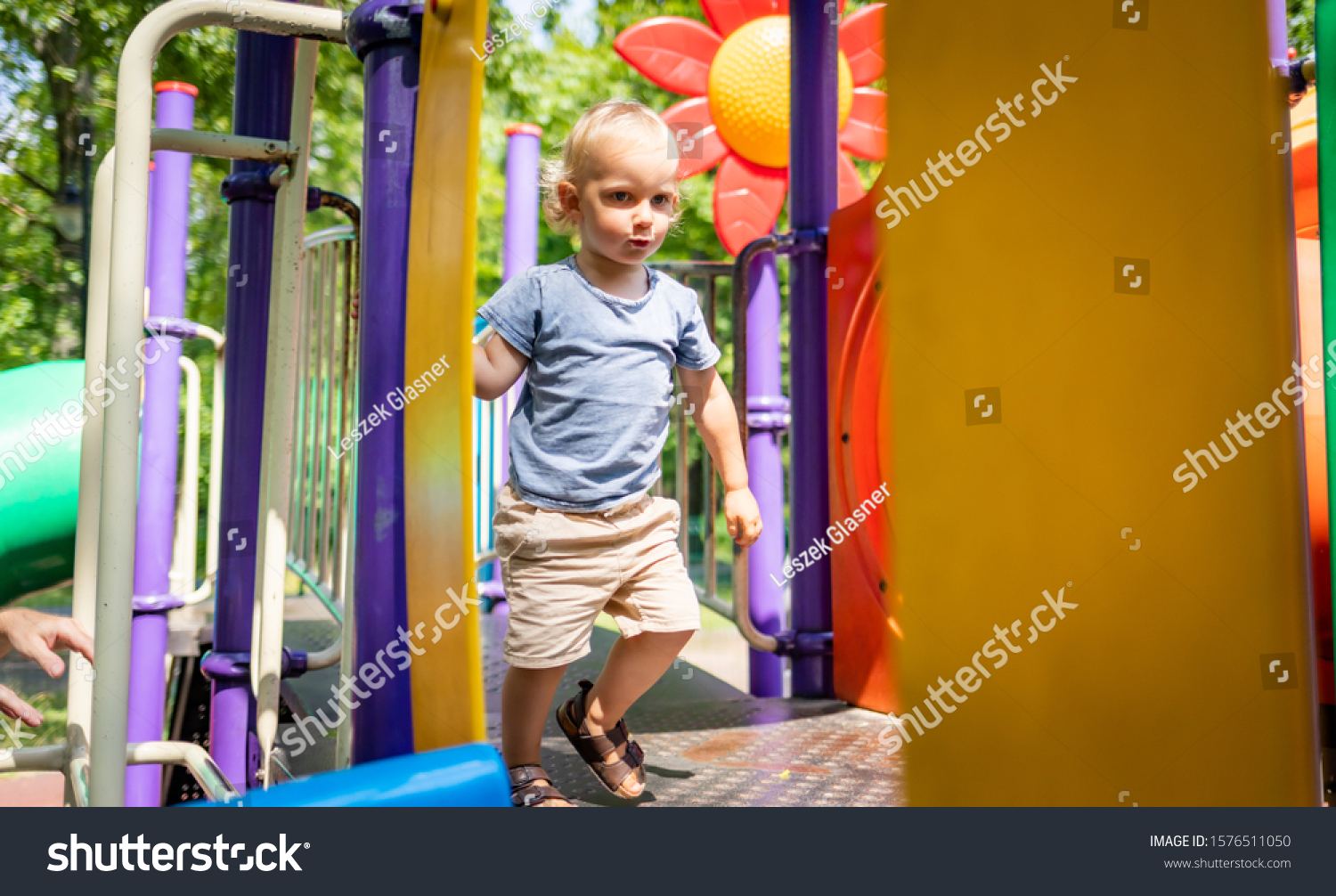 Little child boy playing on playground in the city park #1576511050