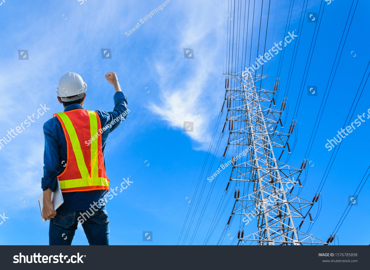 Successful engineers stand against high voltage poles on a blue background. #1576785898