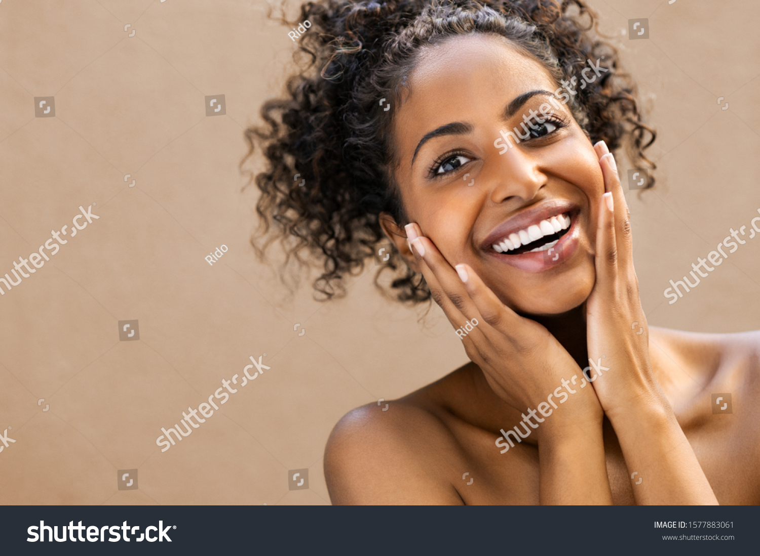 Beautiful young woman smiling after fantastic face treatment. Happy beauty african girl excited after spa treatment isolated on background with copy space. Surpise and astonishment beauty concept. #1577883061