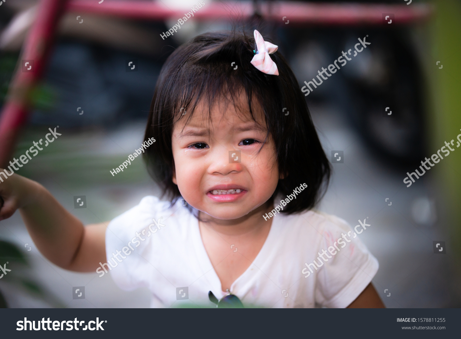 The baby's face was crying with great grief. She cries seriously and frowns. Solid color background. Asian girl 2 years old and 9 months old #1578811255