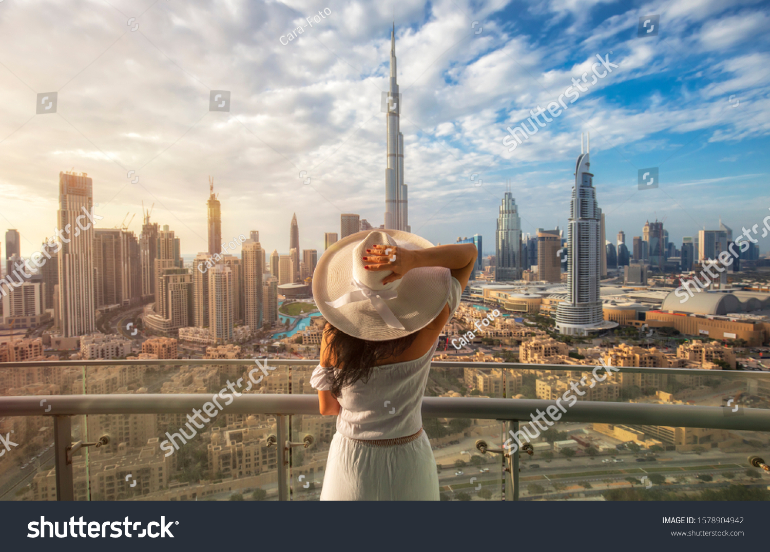 Woman with a white hat is standing on a balcony in front of the skyline from Dubai
Downtown #1578904942