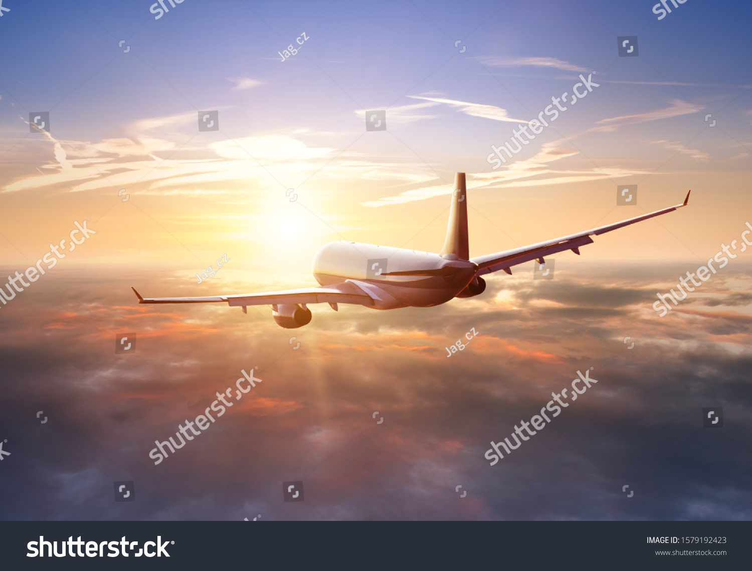 Passengers commercial airplane flying above clouds in sunset light. Concept of fast travel, holidays and business. #1579192423