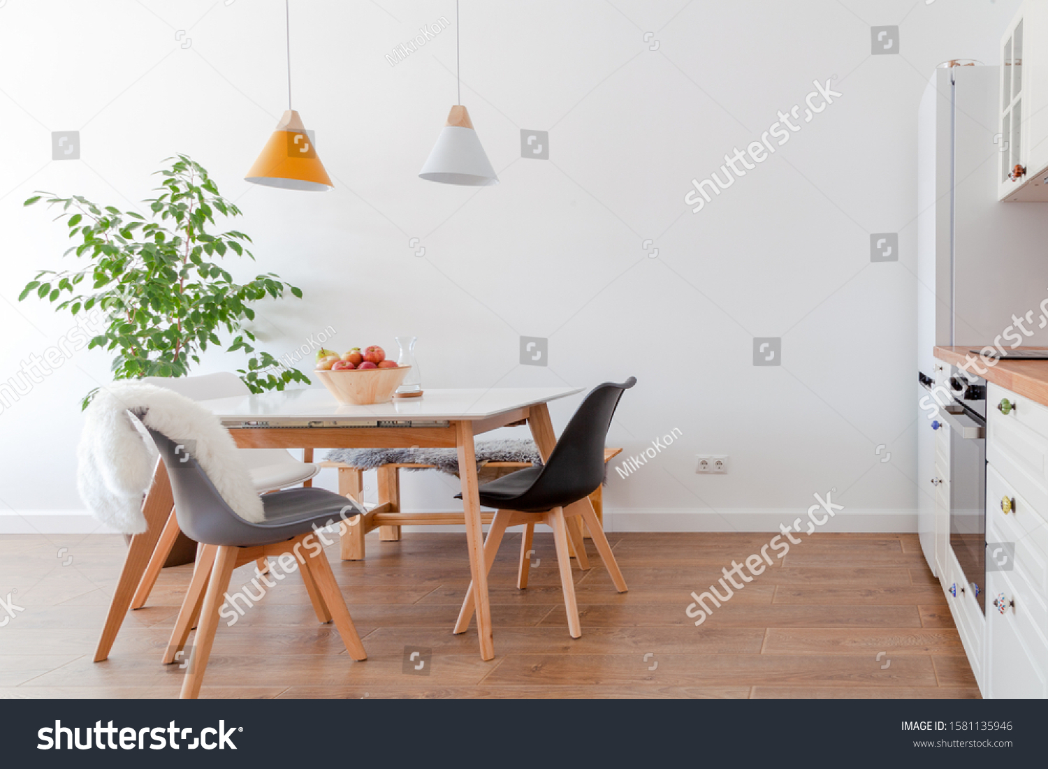 Modern interior of cozy kitchen, dining room, white furniture, lamps above wooden table, chairs, apples, bowl. Concept decor, design, advert, credit, mortgage, home for young family, magazine cover #1581135946