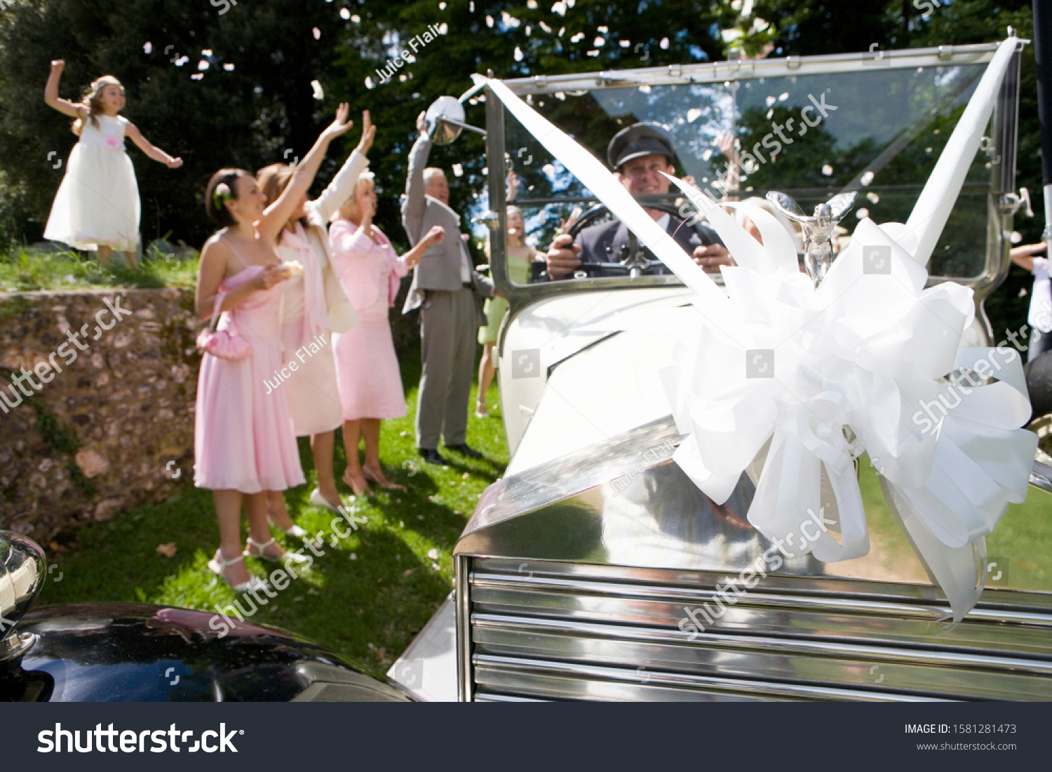 Bridal party waving to bride and groom in vintage car on wedding day #1581281473