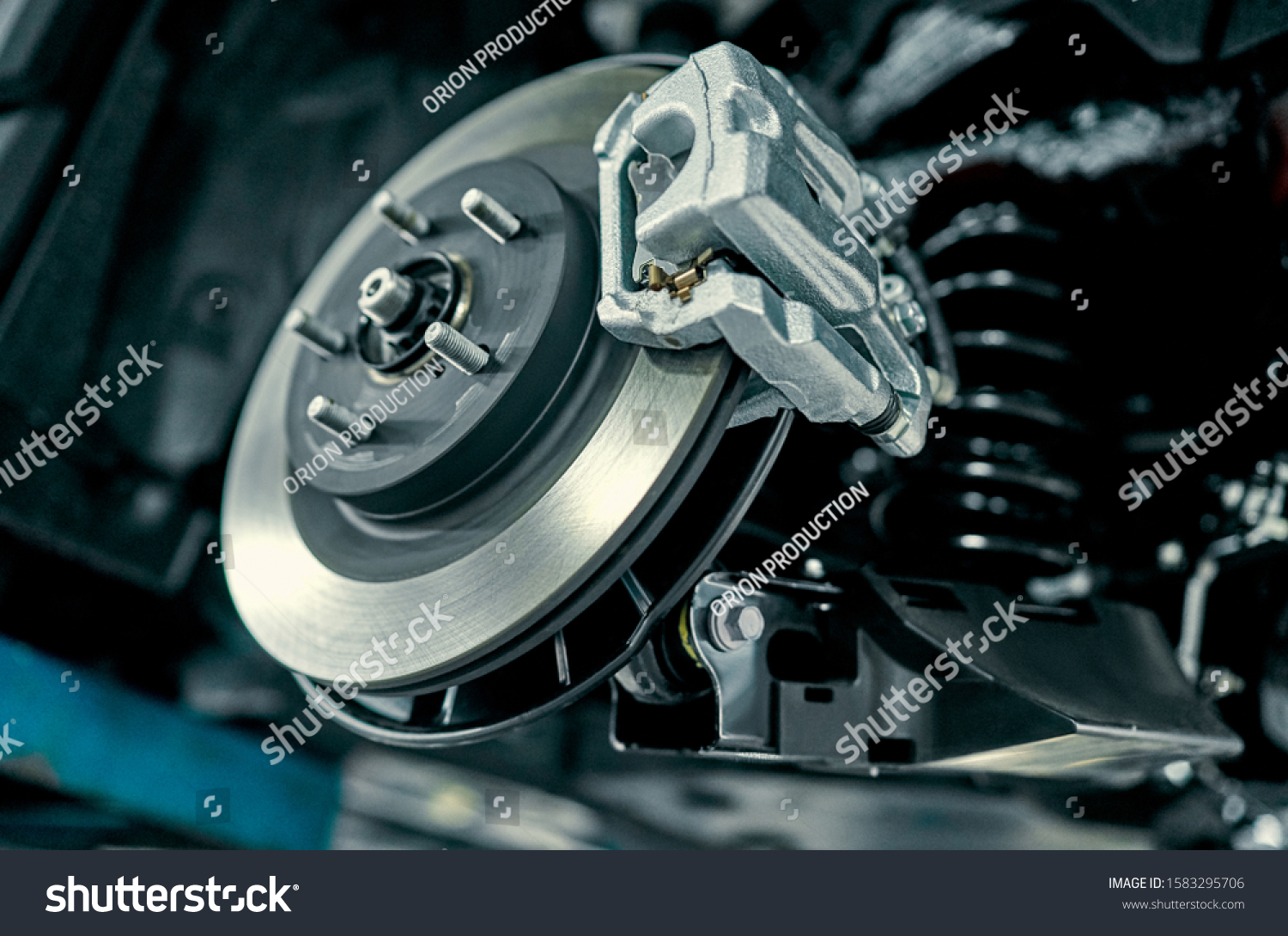 Disc brake of the vehicle for repair, in process of new tire replacement. Car brake repairing in garage.Suspension of car for maintenance brakes and shock absorber systems.Close up. #1583295706