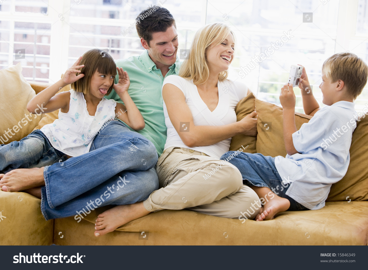 Family sitting in living room with digital camera smiling #15846349