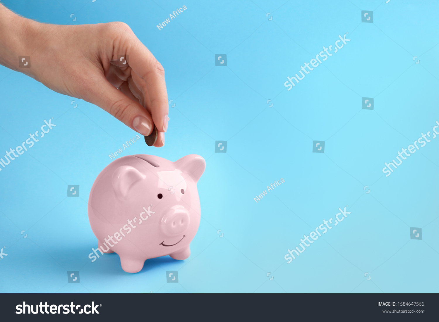 Woman putting coin into piggy bank on light blue background, closeup. Space for text #1584647566