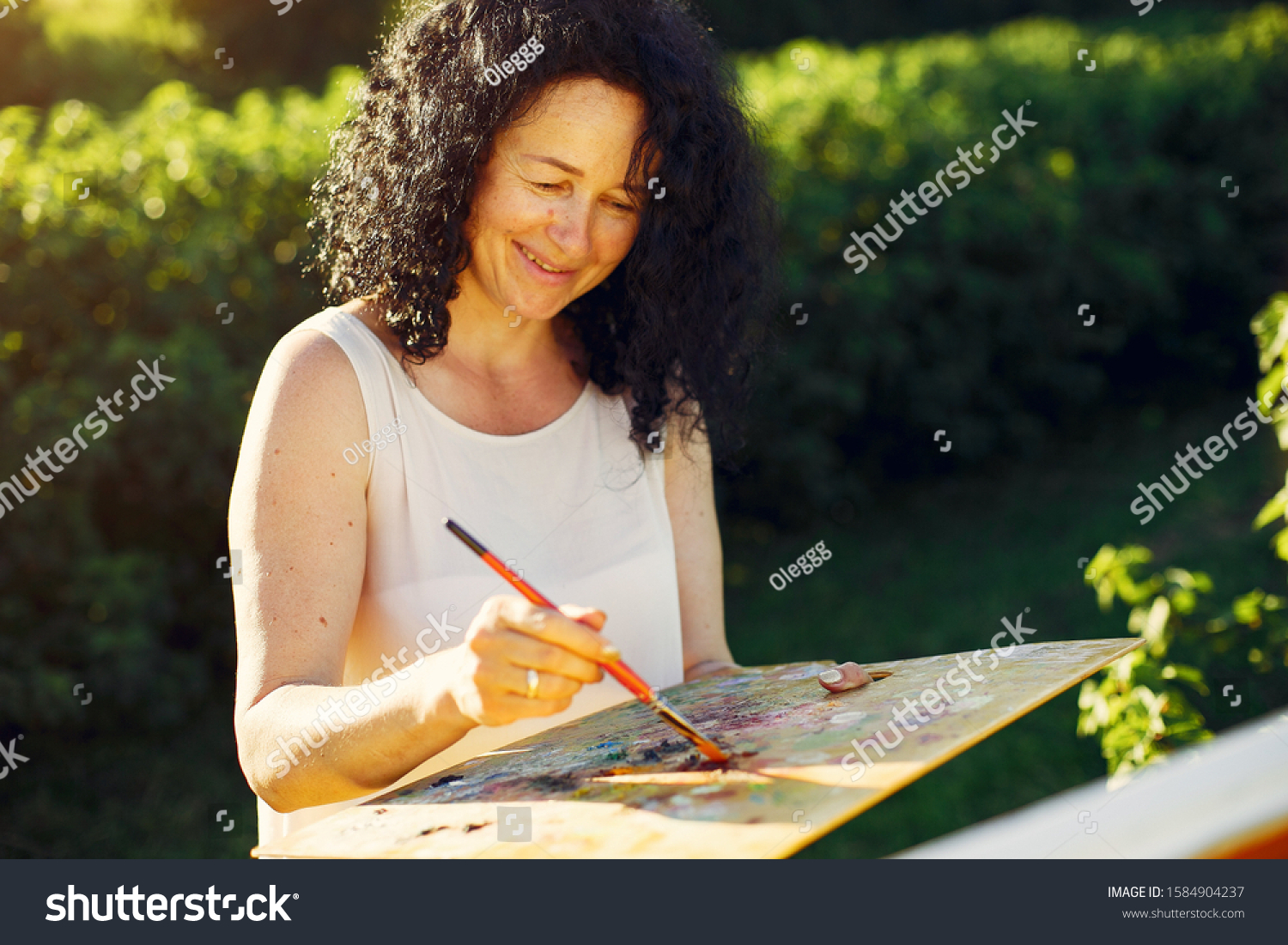 Woman artist painting with oil. Paints in a field #1584904237