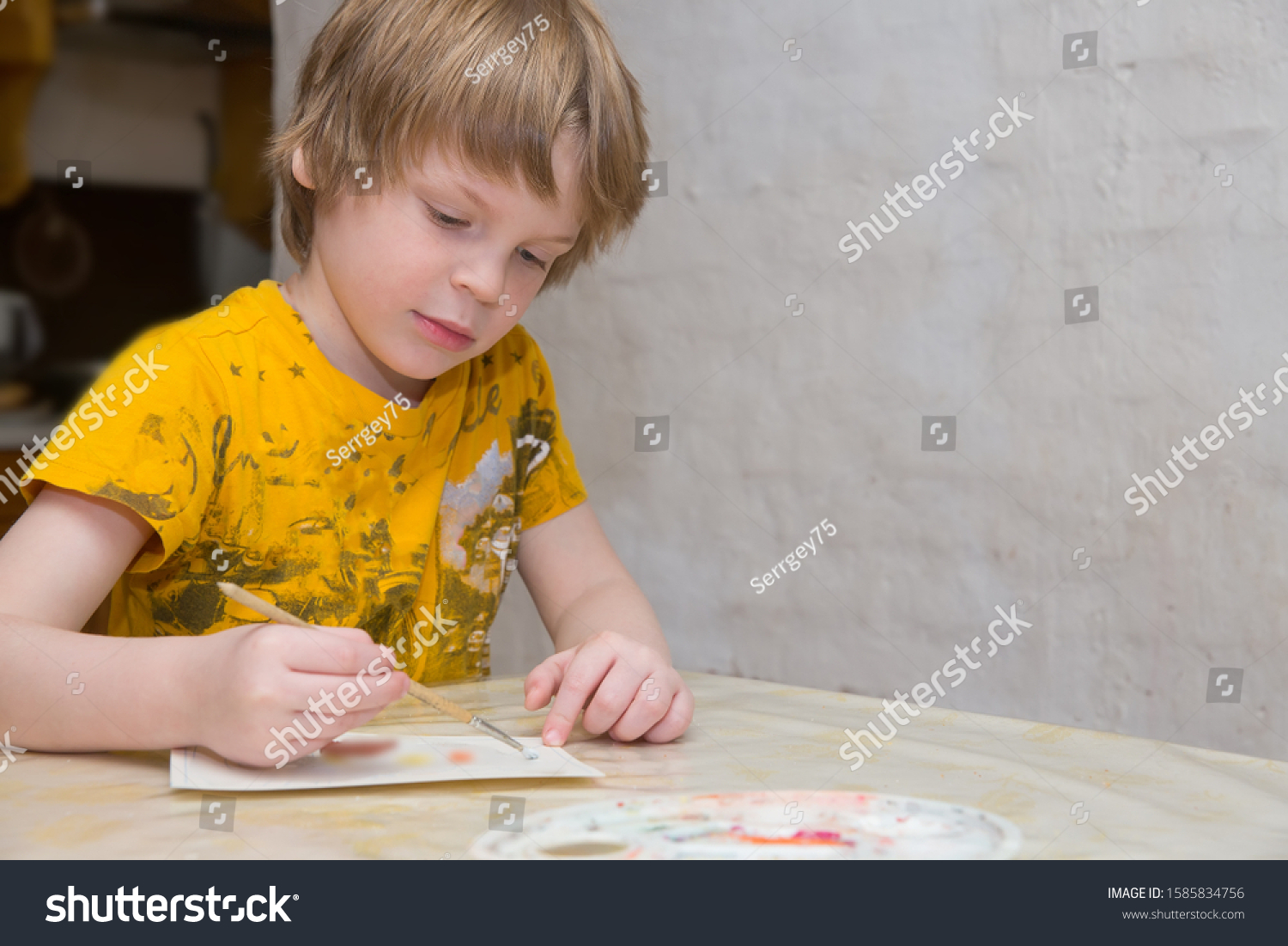 The child learns to draw. A boy of European appearance draws. Photos of real people. #1585834756