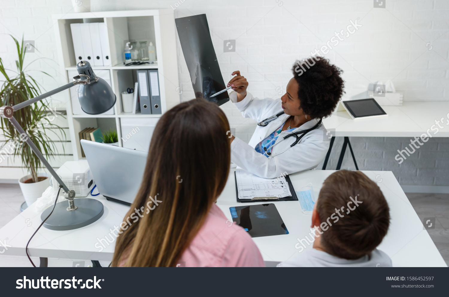 Woman African American doctor examining x ray of child's head #1586452597