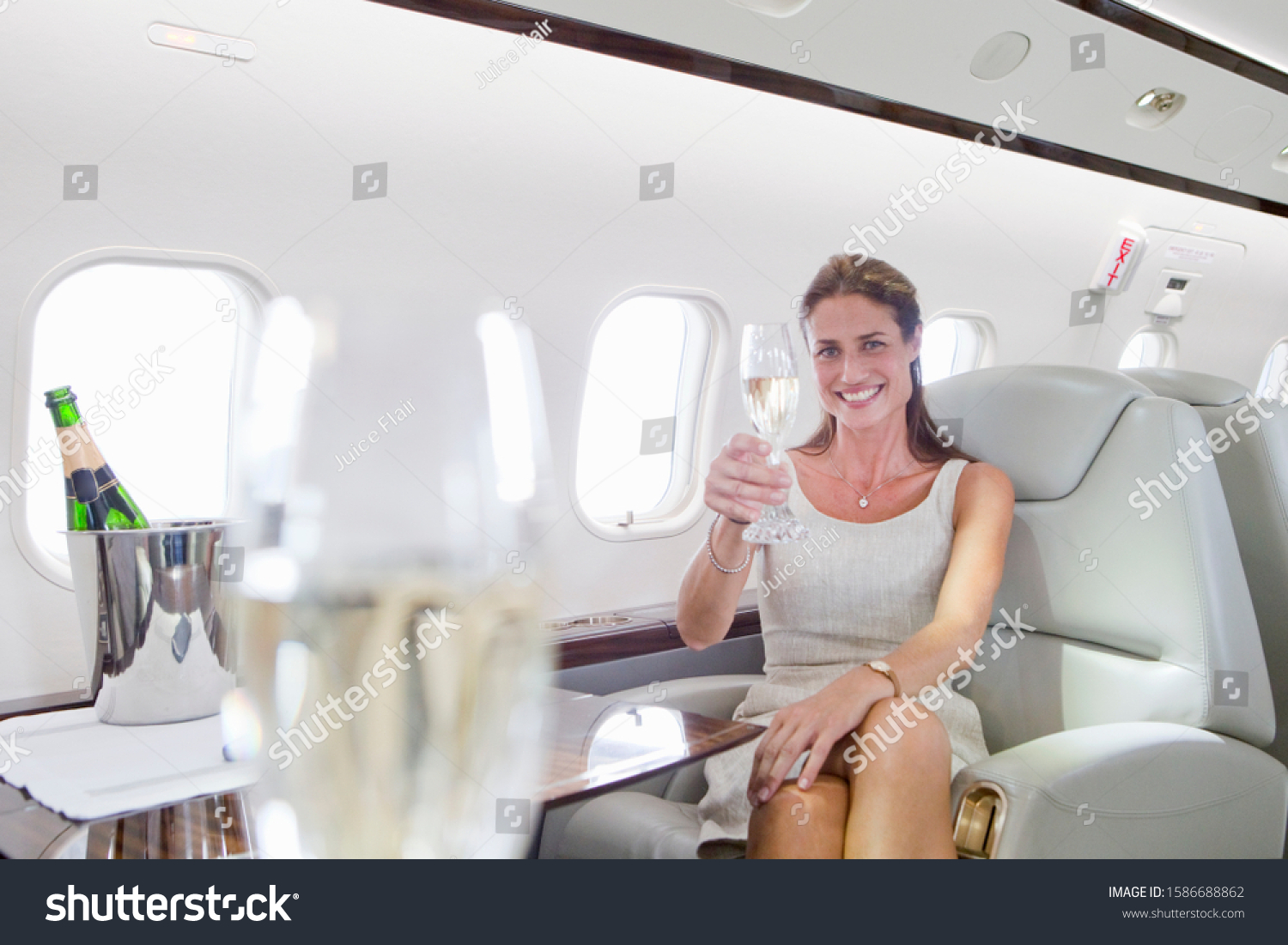 Attractive woman sitting and holding champagne glass in private jet #1586688862