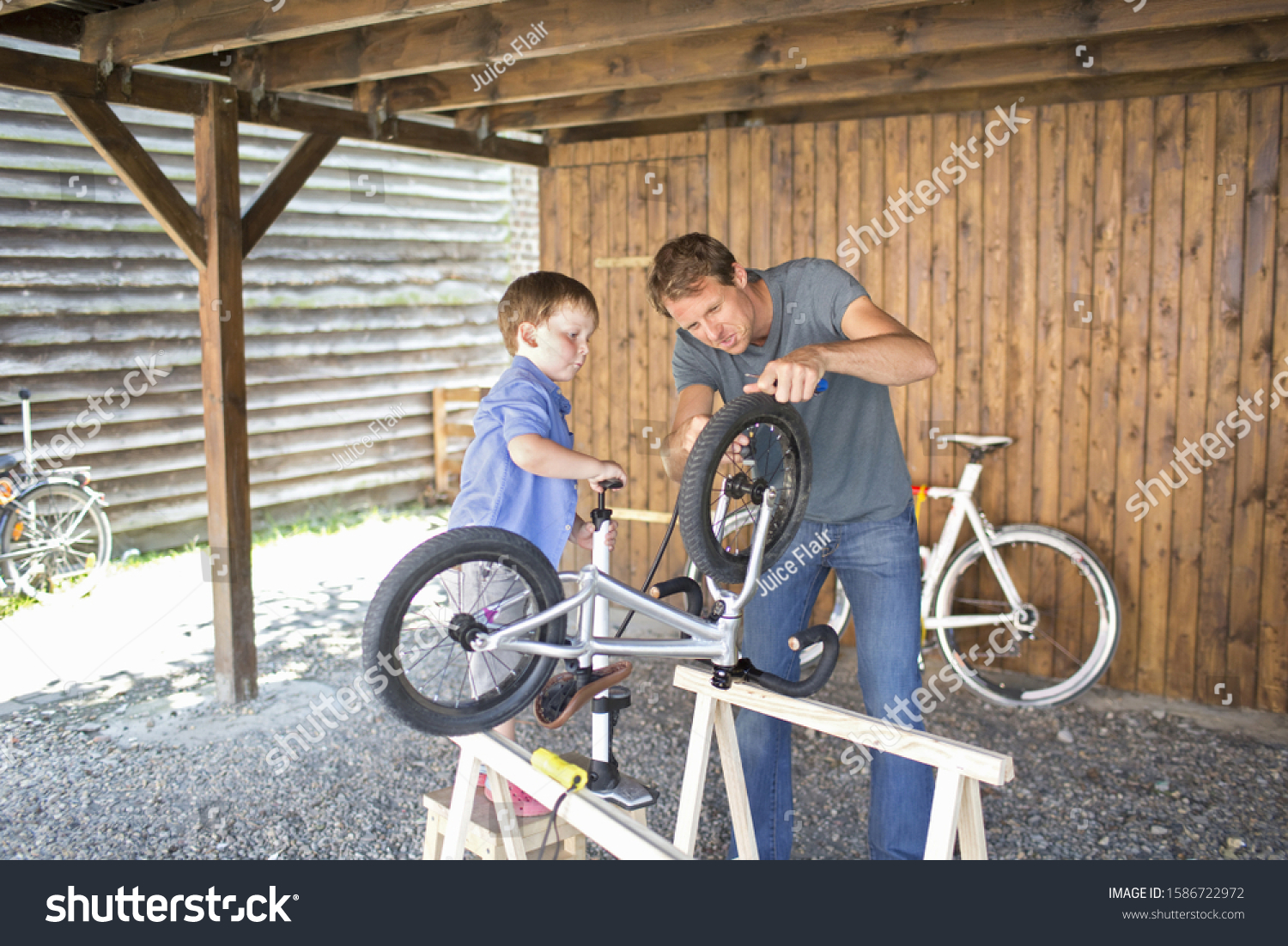 Father And Son Mending Bicycle In Garage At Home #1586722972