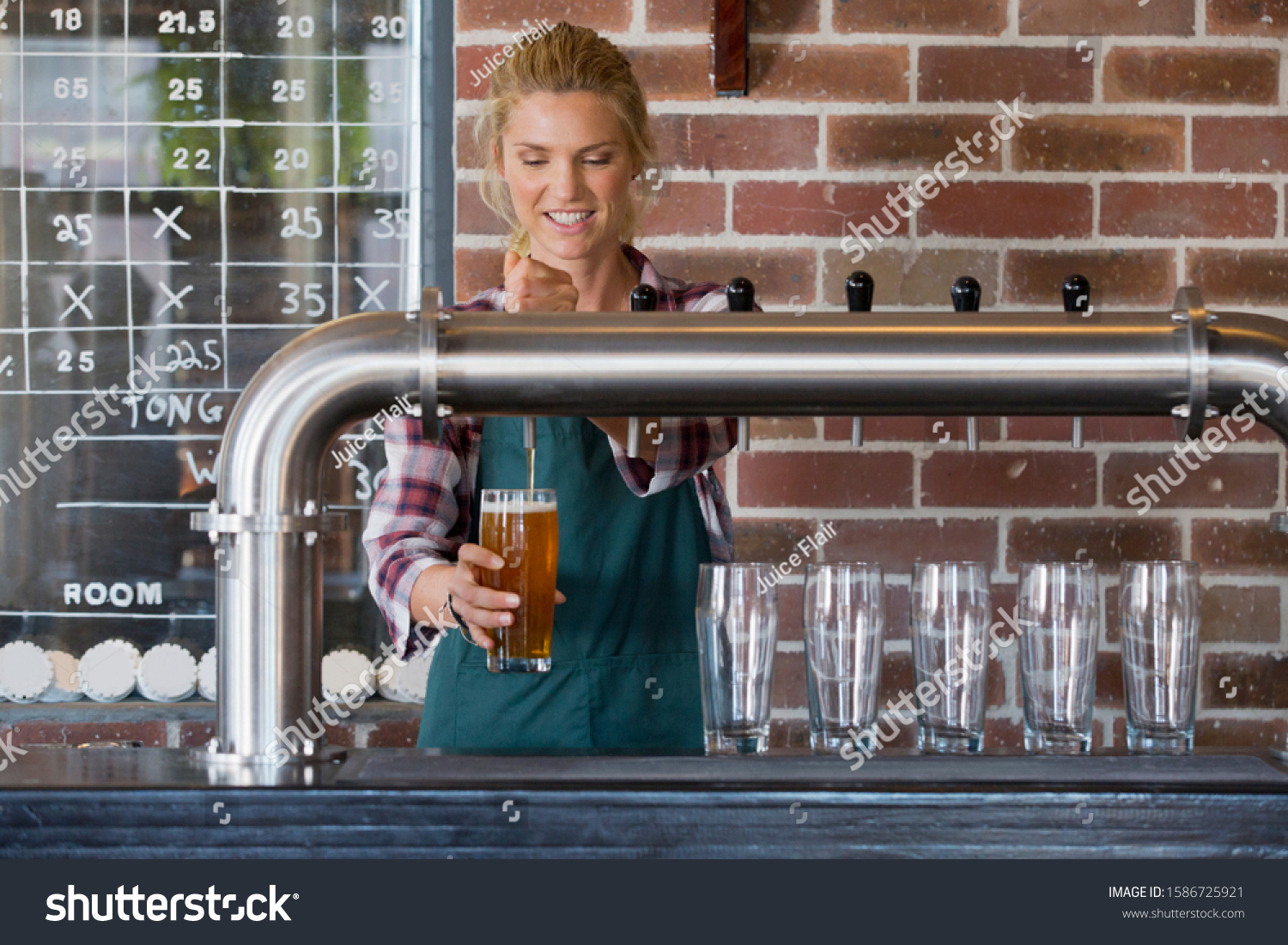 Female Bartender Pouring Pint Of Beer Behind Counter #1586725921