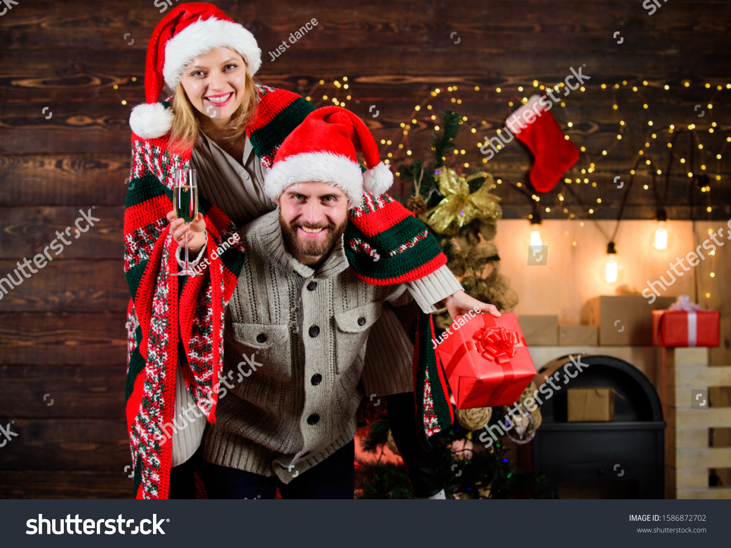 Celebrating together. Celebrating winter holiday. Christmas fun. Interesting ideas celebration. Man and woman santa claus hats cheerful celebrating new year. Merry christmas. Guy piggybacking girl. #1586872702