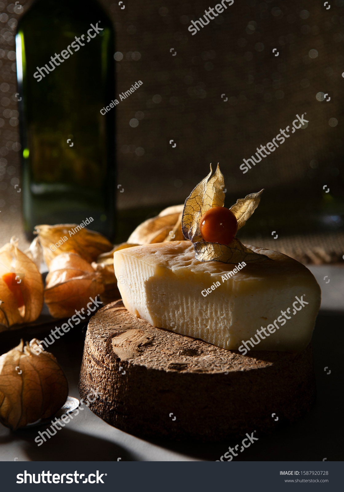 Half ripened cheese from Minas Gerais. Selective focus. Brazilian Christmas table .Exotic fruit, physalis, focused .Focused white lights background. Seen up close. Vertical. #1587920728