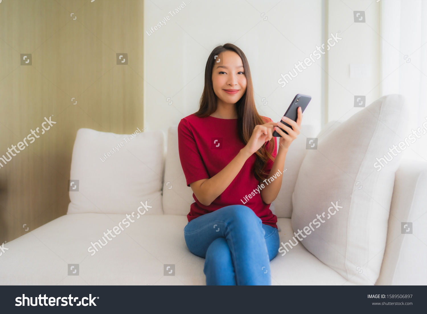 Portrait beautiful young asian women using mobile or smart phone on sofa in living room interior #1589506897