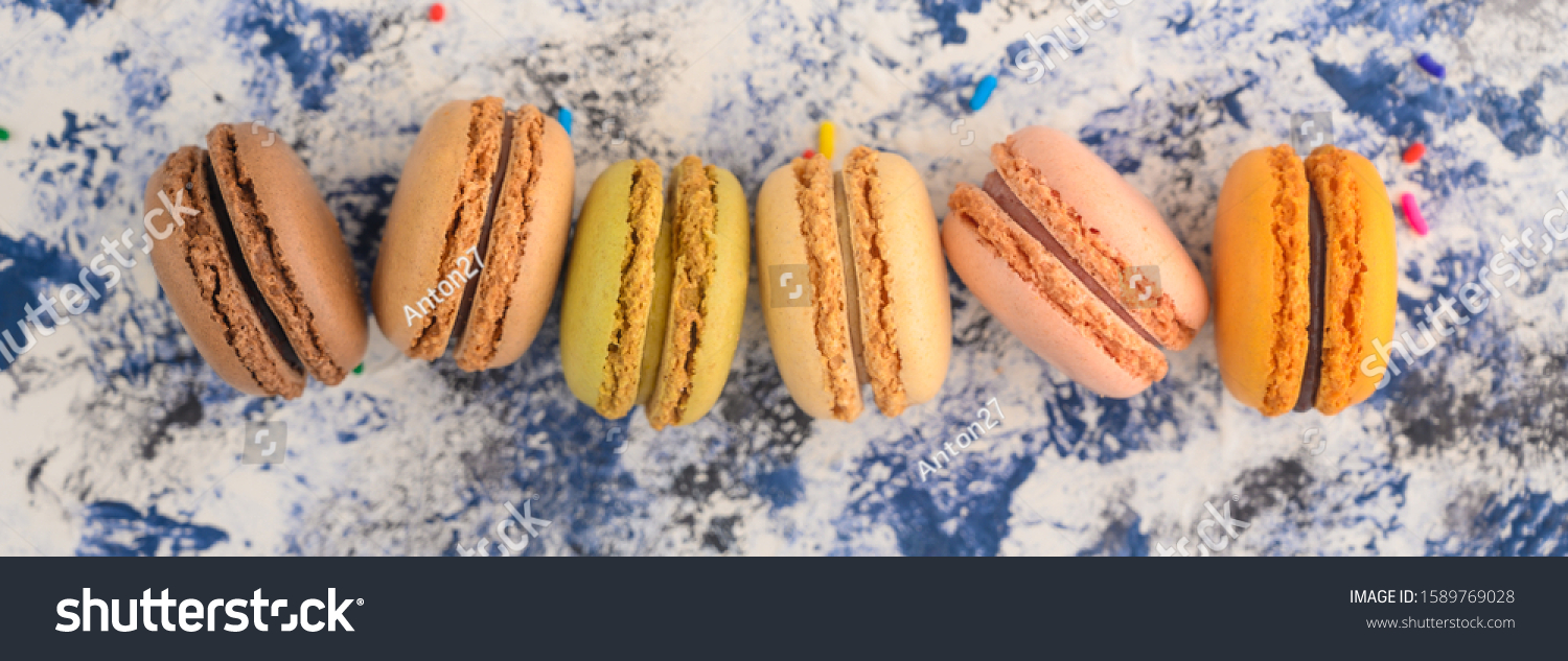 French macaroons in a row of colored, on a colored background with colored caramel sweets. #1589769028