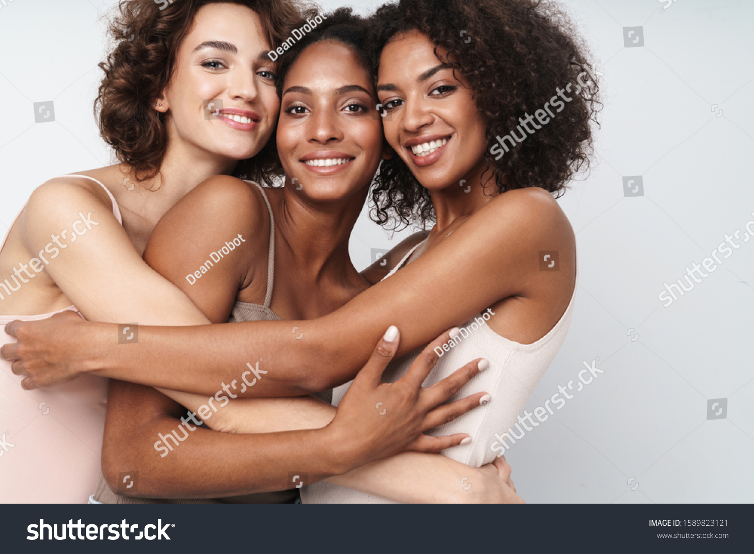 Portrait of three adorable multiethnic women smiling and hugging together isolated over white background #1589823121