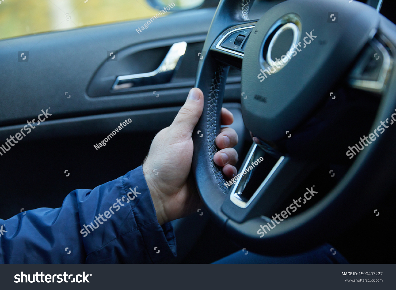 Male driver hands holding steering wheel #1590407227