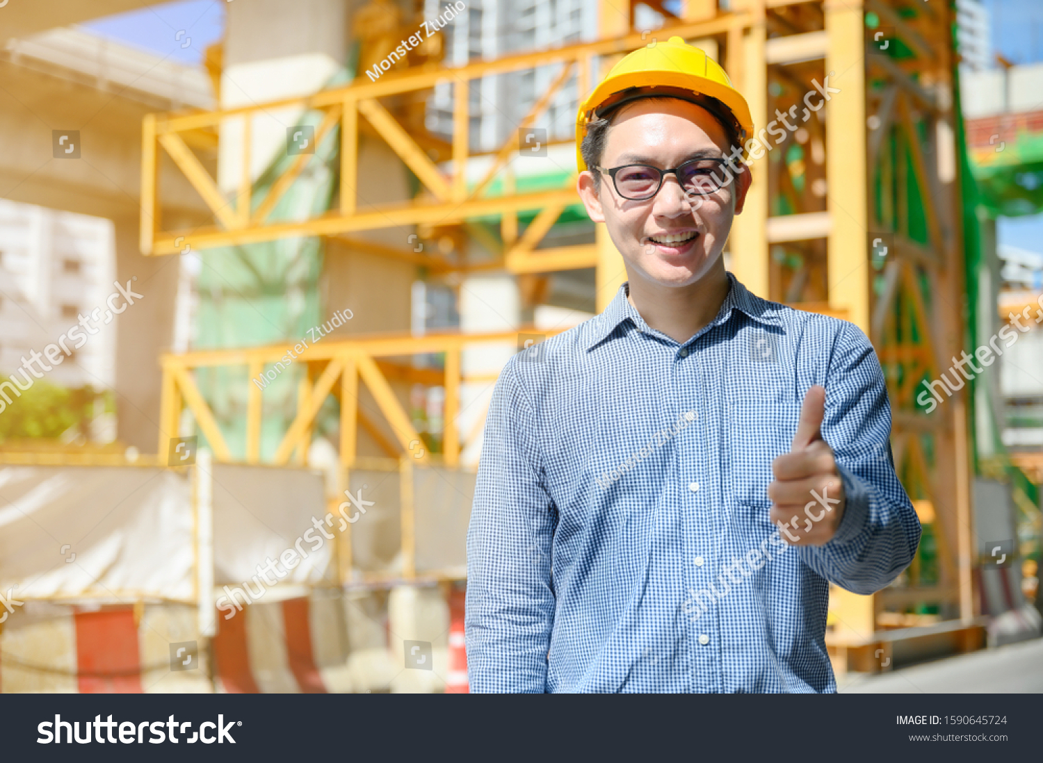 New generation of asian engineers are working on the construction site. He looks handsome and smart. #1590645724